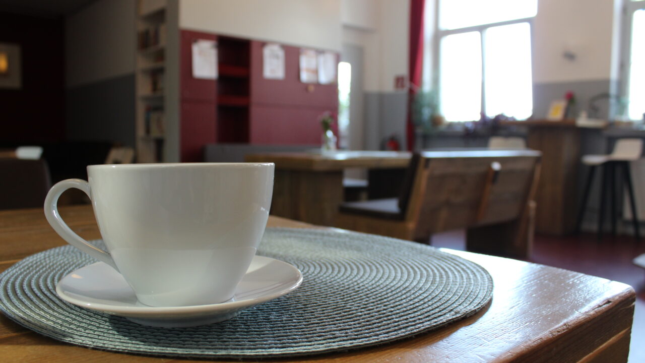 Kaffeetasse auf Tisch, im Hintergrund das Café